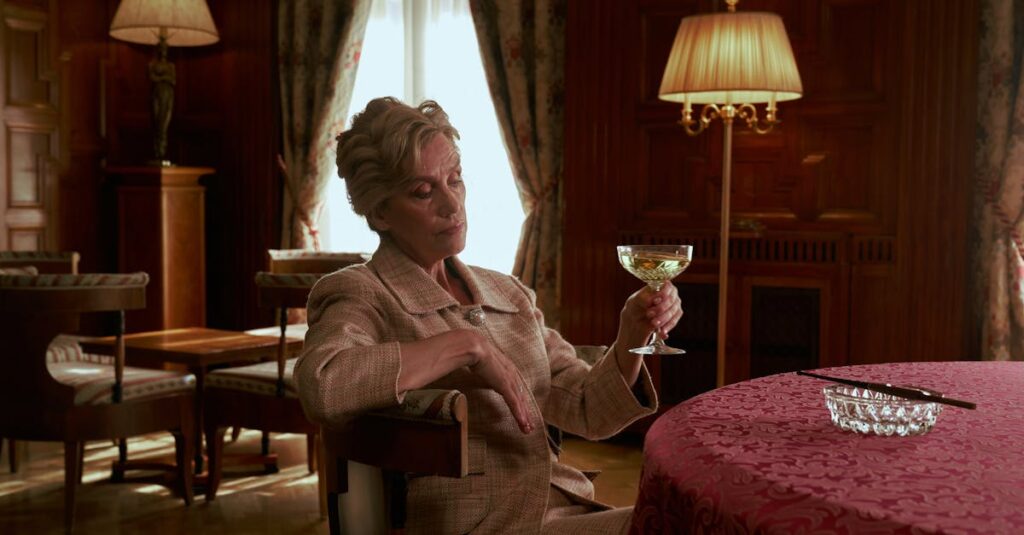 Elegant Woman Sitting by the Table and Holding Glass of Wine