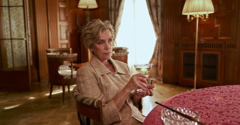 Woman Sitting by the Table with a Glass of Wine