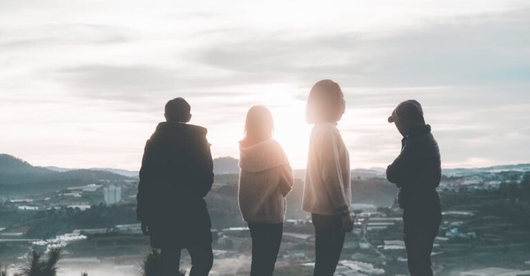 Four People Standing on Top of Hill during Sunset