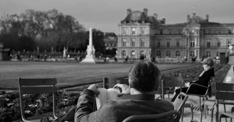 Man Sitting on Palace Courtyard and Reading Book