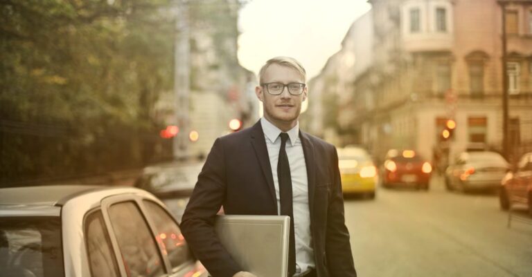 Determined smiling businessman with laptop on street