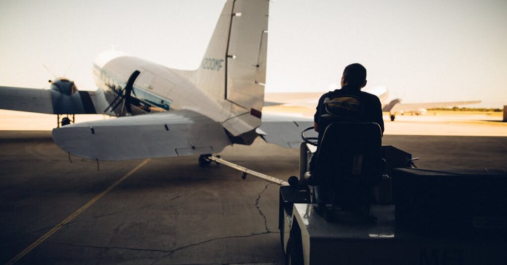 Silhouette of worker driving baggage carrier on paved airfield with airplane before flight