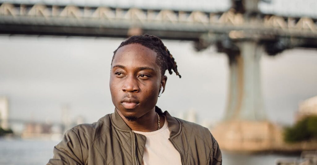 Serious black man using mobile phone while standing near river