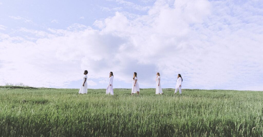 *+&*Women in White Dresses Standing on Green Grass Field Under Cloudy Sky