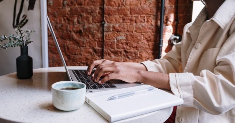 Person in White Long Sleeve Shirt Using Macbook Pro