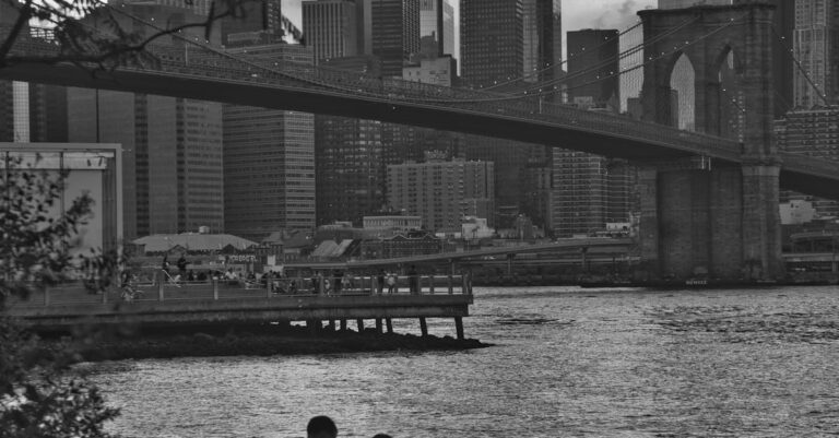 Grayscale Photo of a Couple Sitting on Rocks