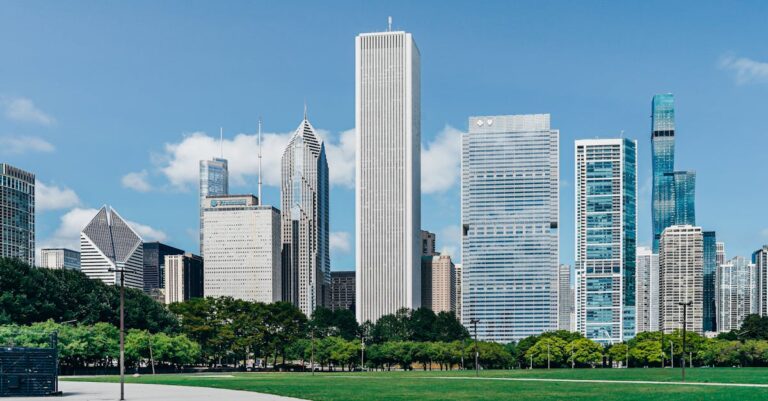 Modern city district with skyscrapers near green lawn