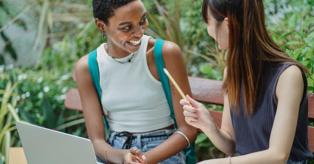 Joyful multiethnic female students working on assignment in park