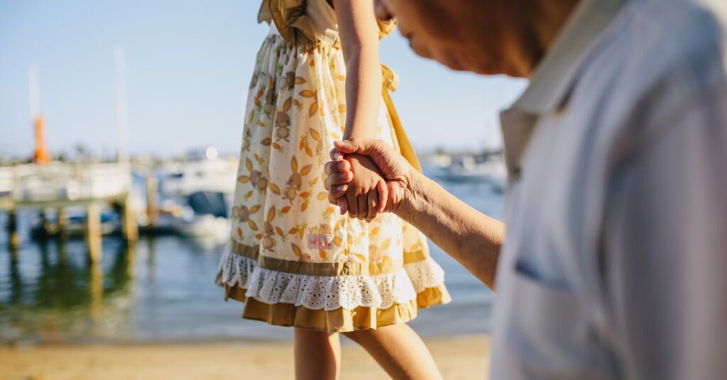 Grandfather Holding His Granddaughter's Hand while Walking