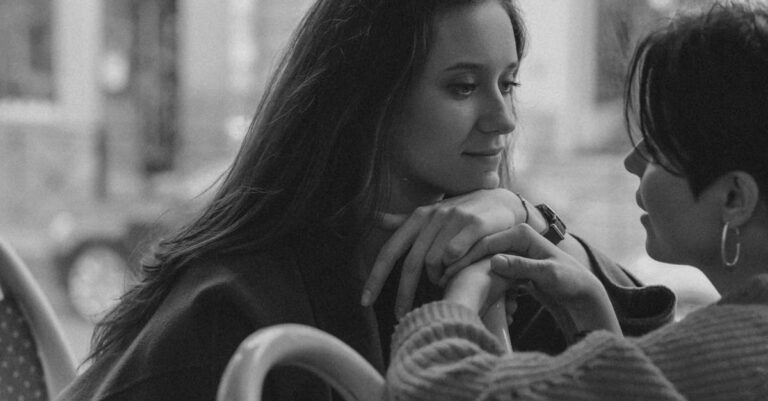 Grayscale Photo of Girls Couple Looking at Each Other in the Bus