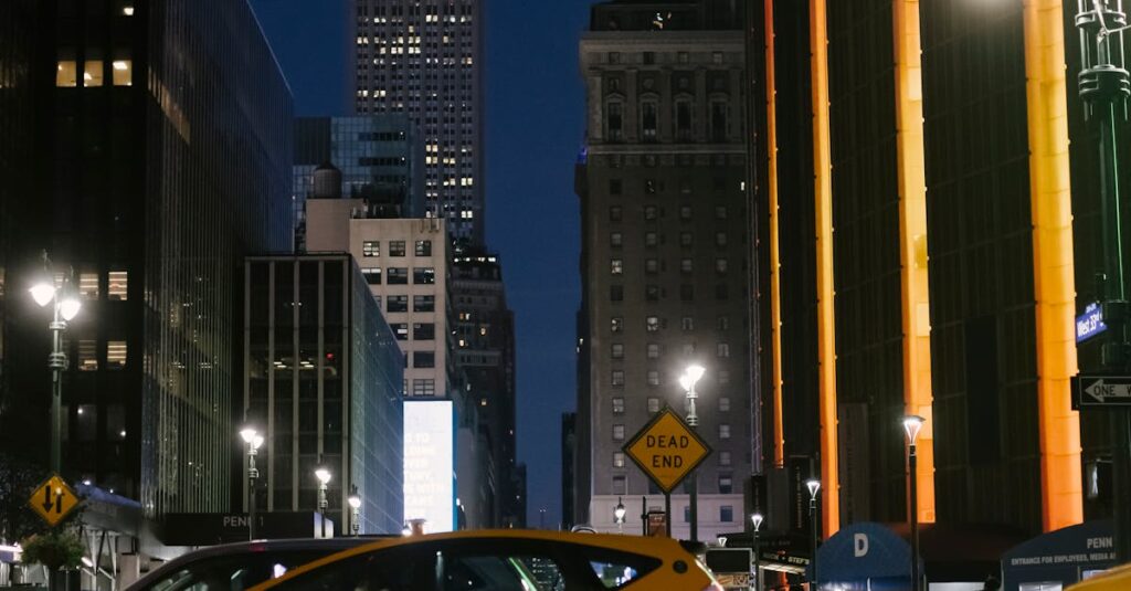 Contemporary cars riding on night city street near illuminated skyscrapers