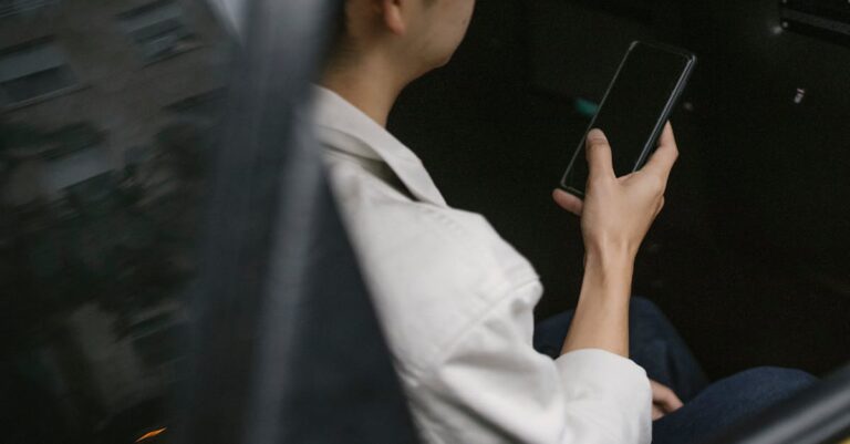 High angle of taxi passenger using smartphone while sitting on backseat