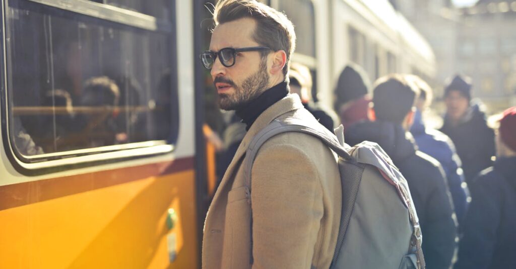 Man in Brown Coat and Gray Backpack Posing for a Photo