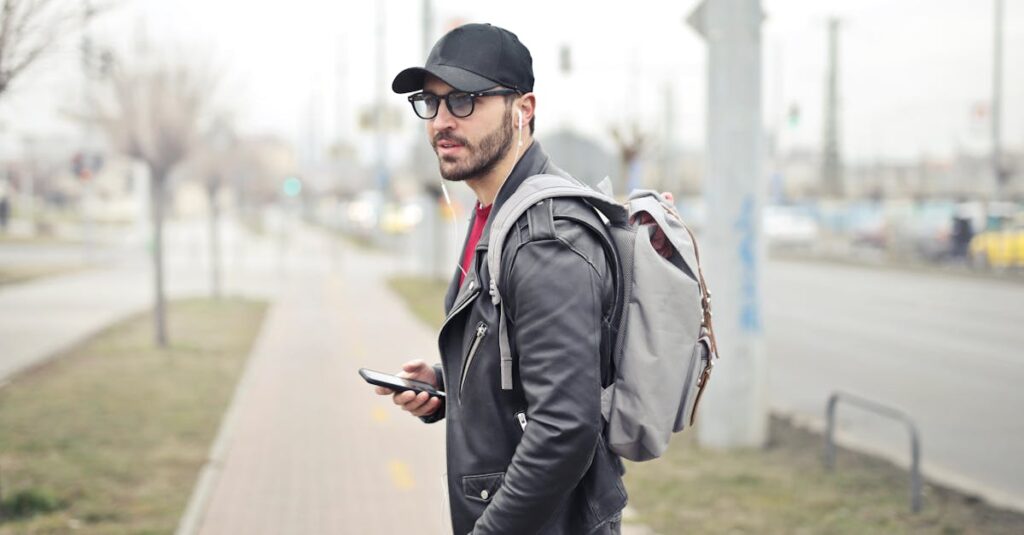 Man Wearing Black Leather Jacket Holding Smartphone