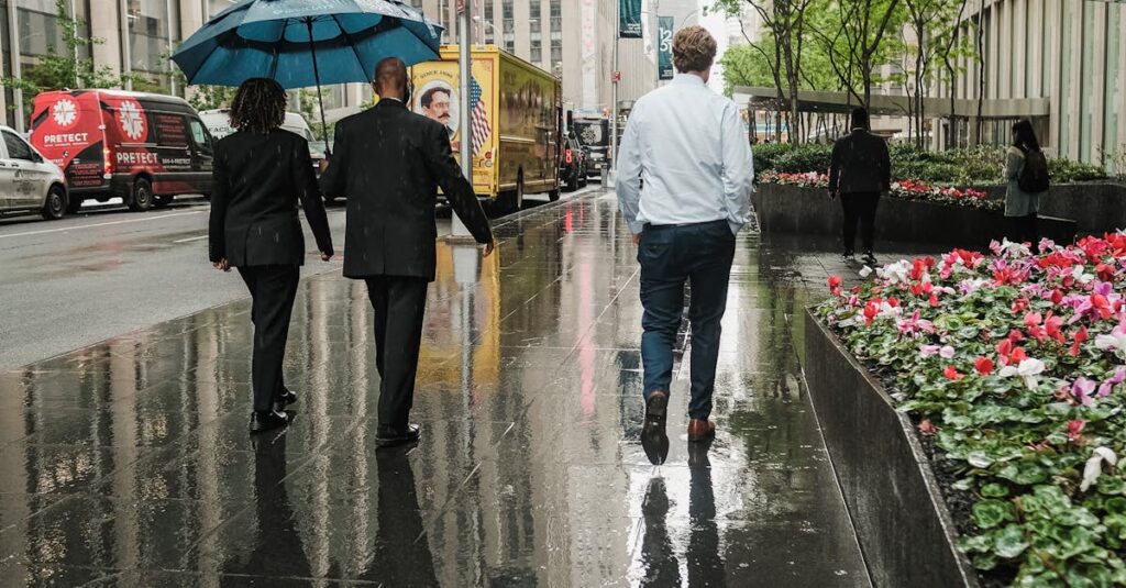 Back View of People Walking on Sidewalk during Rainy Day