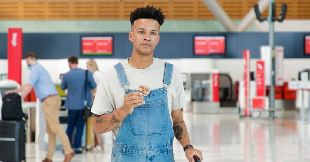 Man Wearing Denim Jumper Holding a Cookie in Blurred Background