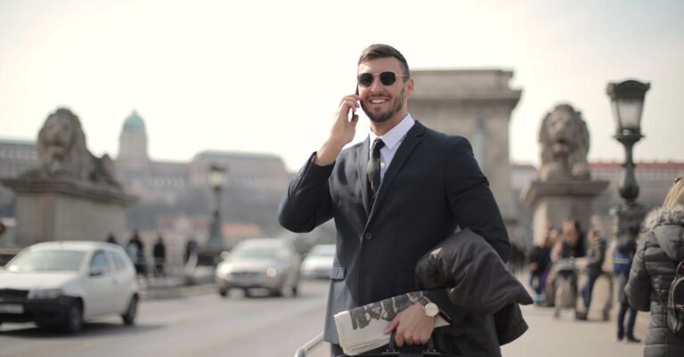 Man in Black Suit Jacket and Black Sunglasses While Using Smartphone