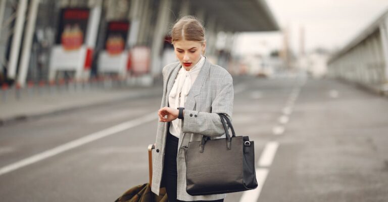 Worried young businesswoman with suitcase hurrying on flight on urban background