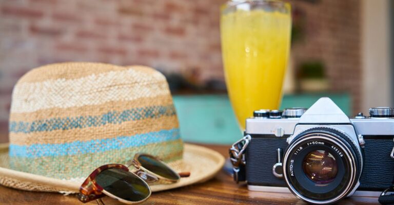 Gray and Black Dslr Camera Beside Sun Hat and Sunglasses