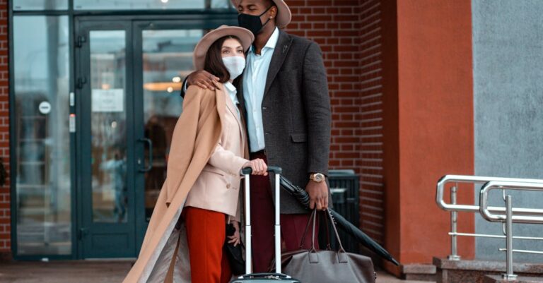 Man and Woman With Face Masks Waiting Outside A Building