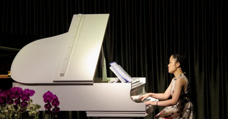 A woman plays a white piano on stage surrounded by flowers, showcasing classical elegance.