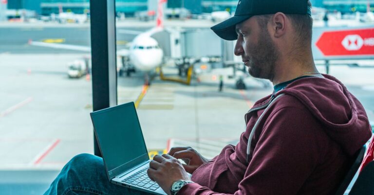 Man in Hoodie Jacket Sitting on a Chair Using Laptop