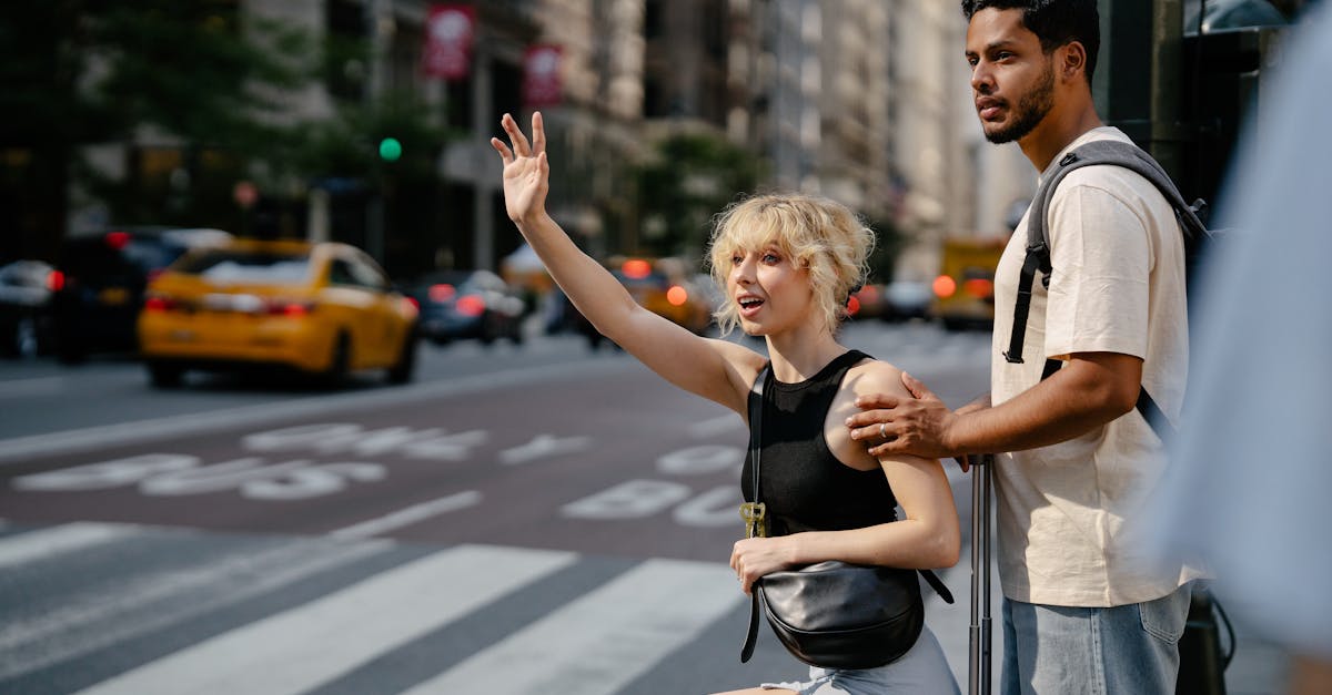 A young couple hailing a yellow cab on a bustling city street, exuding urban life.