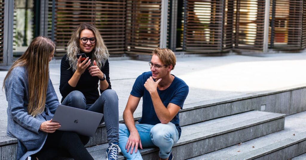 Three young professionals having a friendly chat while sitting on outdoor steps.