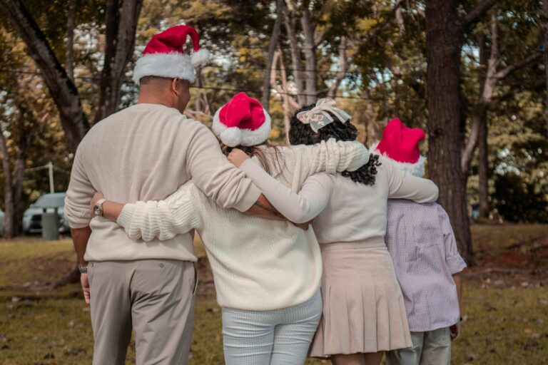 A diverse family embraces outdoors in festive Santa hats, creating a joyful atmosphere.