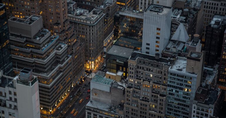 A dramatic aerial view of illuminated skyscrapers in Manhattan, New York City, showcasing urban architecture and city life at night.