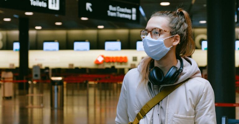 Woman in an airport wearing a face mask for health safety during travel.