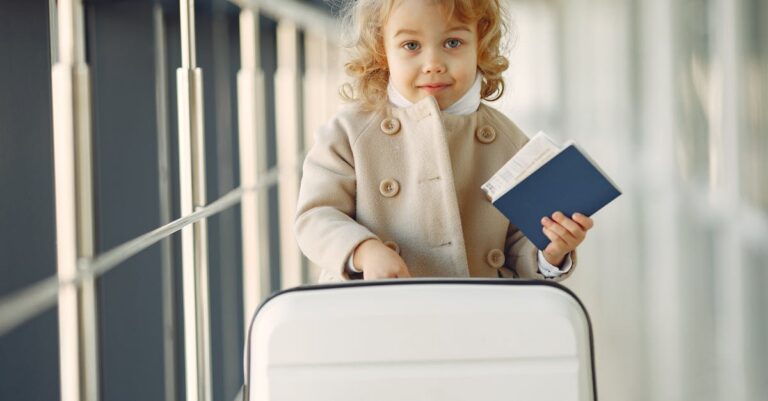 Cute child with passport and suitcase in a modern airport terminal.