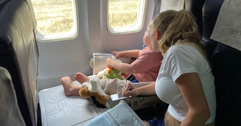 Mother and child sitting inside airplane, enjoying scenic view through windows during flight travel.