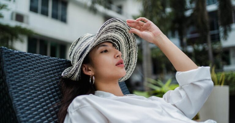 Stylish young ethnic woman recreating on lounger in hotel garden