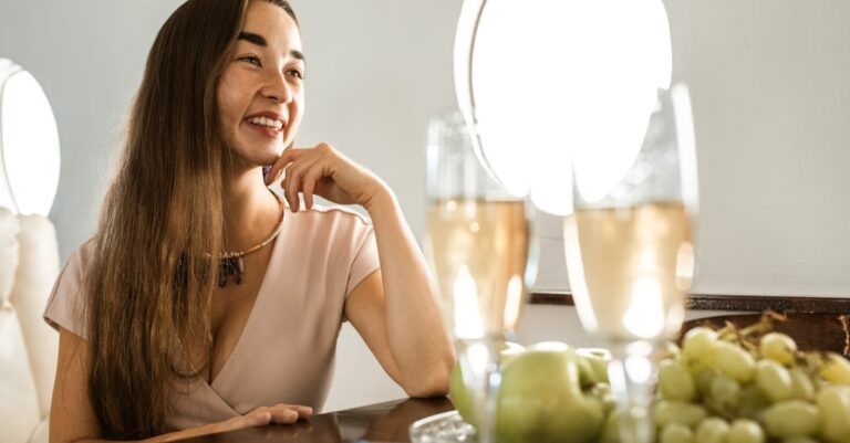 Woman relaxing in a private jet with champagne and fresh fruit, epitomizing luxury travel.