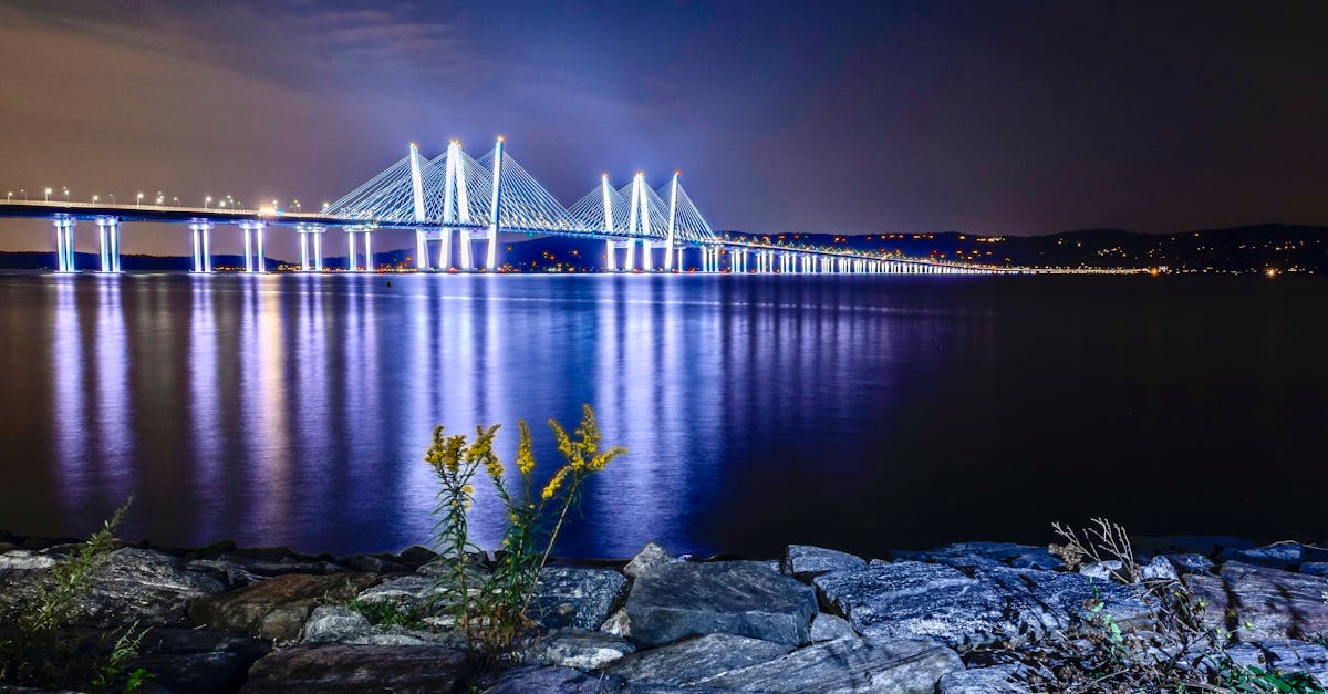 Stunning night view of the illuminated Tappan Zee Bridge over the Hudson River with reflections on the water.