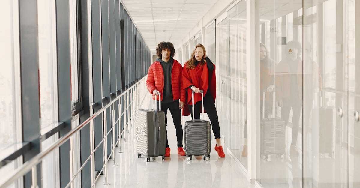 A Couple Standing on a Hallway while Holding Luggages