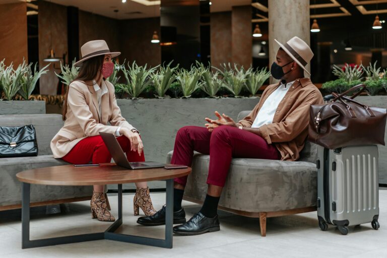 Caucasian woman and Black man meeting in hotel lobby wearing face masks.