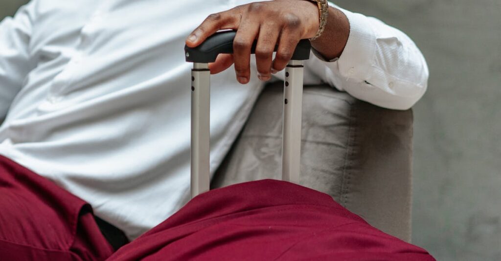 Close-up of a business traveler's hand resting on a suitcase handle, dressed in casual attire.