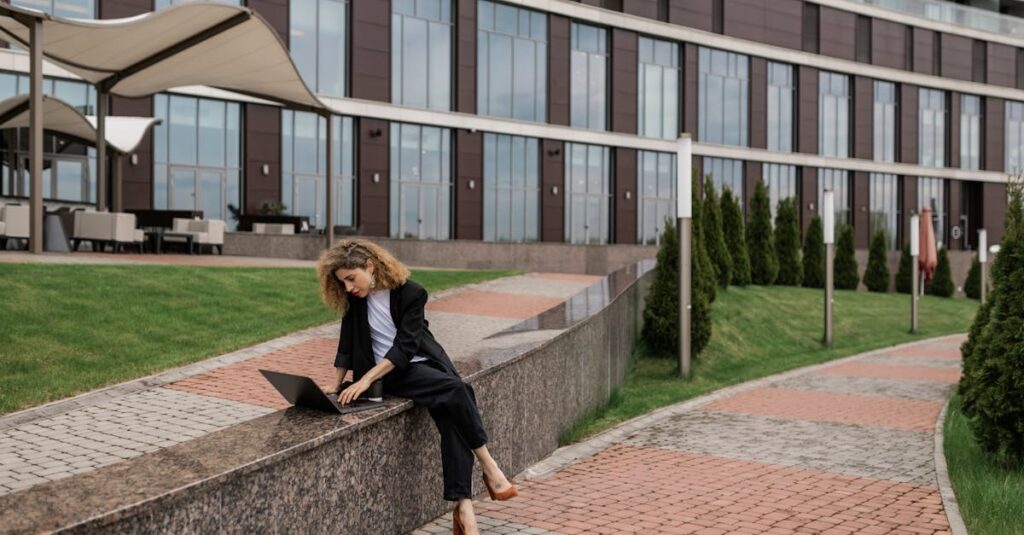 Woman in Black Coat Using Laptop Outside Building