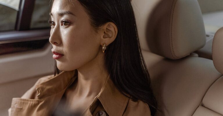 Woman in Brown Coat Sitting on White Leather Chair