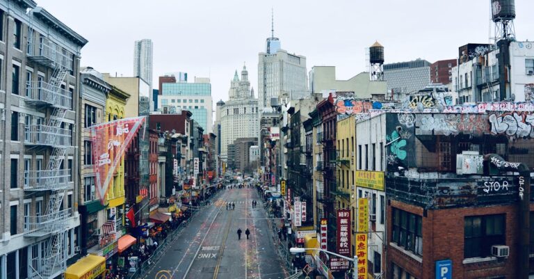 An urban street view of New York City's Chinatown with vibrant buildings and street art.