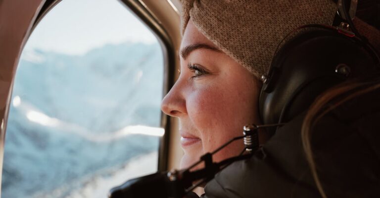 A woman enjoys a helicopter view of Canterbury's snowy mountains during winter.