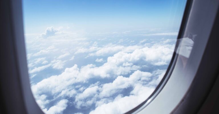 Breathtaking view of clouds and blue sky through an airplane window during flight.