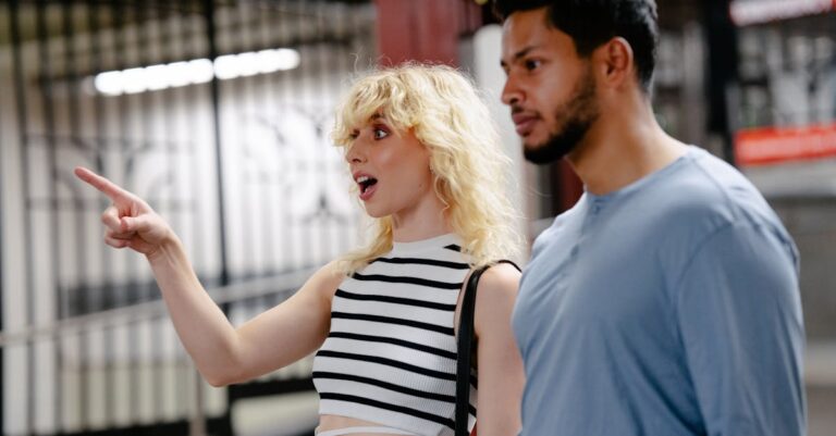 A man and woman in a subway station having a lively conversation, pointing in direction.