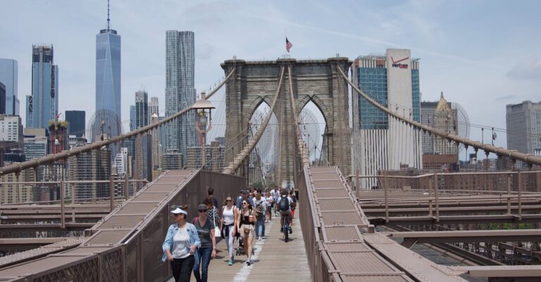 View of the Brooklyn Bridge with pedestrians, set against the iconic New York City skyline.