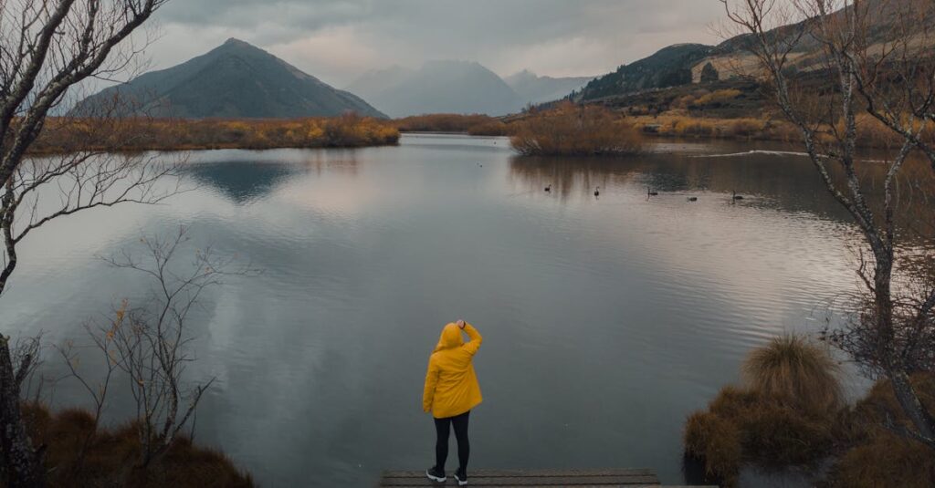 Person in yellow raincoat at Glenorchy Lake, Otago with a mountain backdrop.