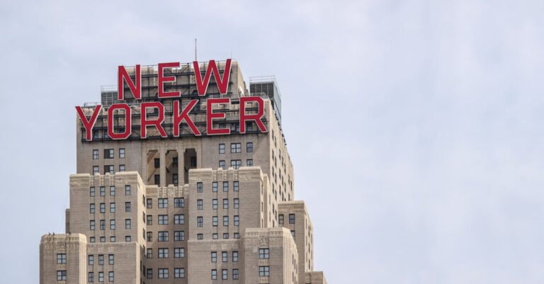 Iconic New Yorker Hotel with its famous sign in New York City against a clear sky.