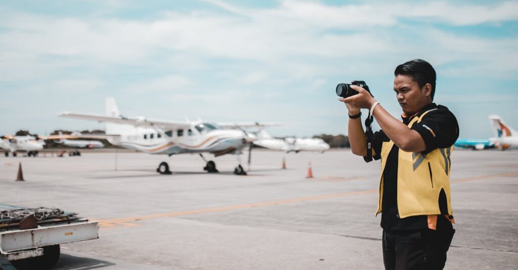 Asian man taking photos of planes on airport tarmac during the day.