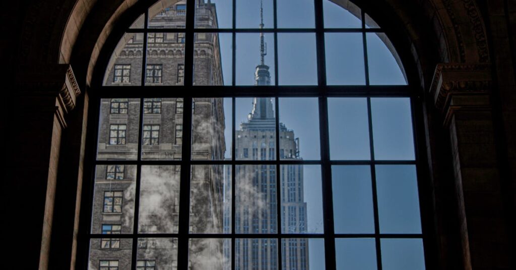 View of the Empire State Building framed by an arched window, capturing its iconic New York City architecture.